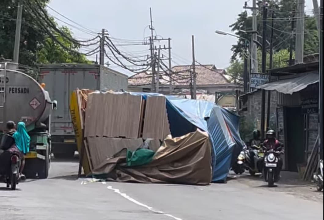 Overload, Truk Bermuatan Triplek Terguling di Krikilan Gresik